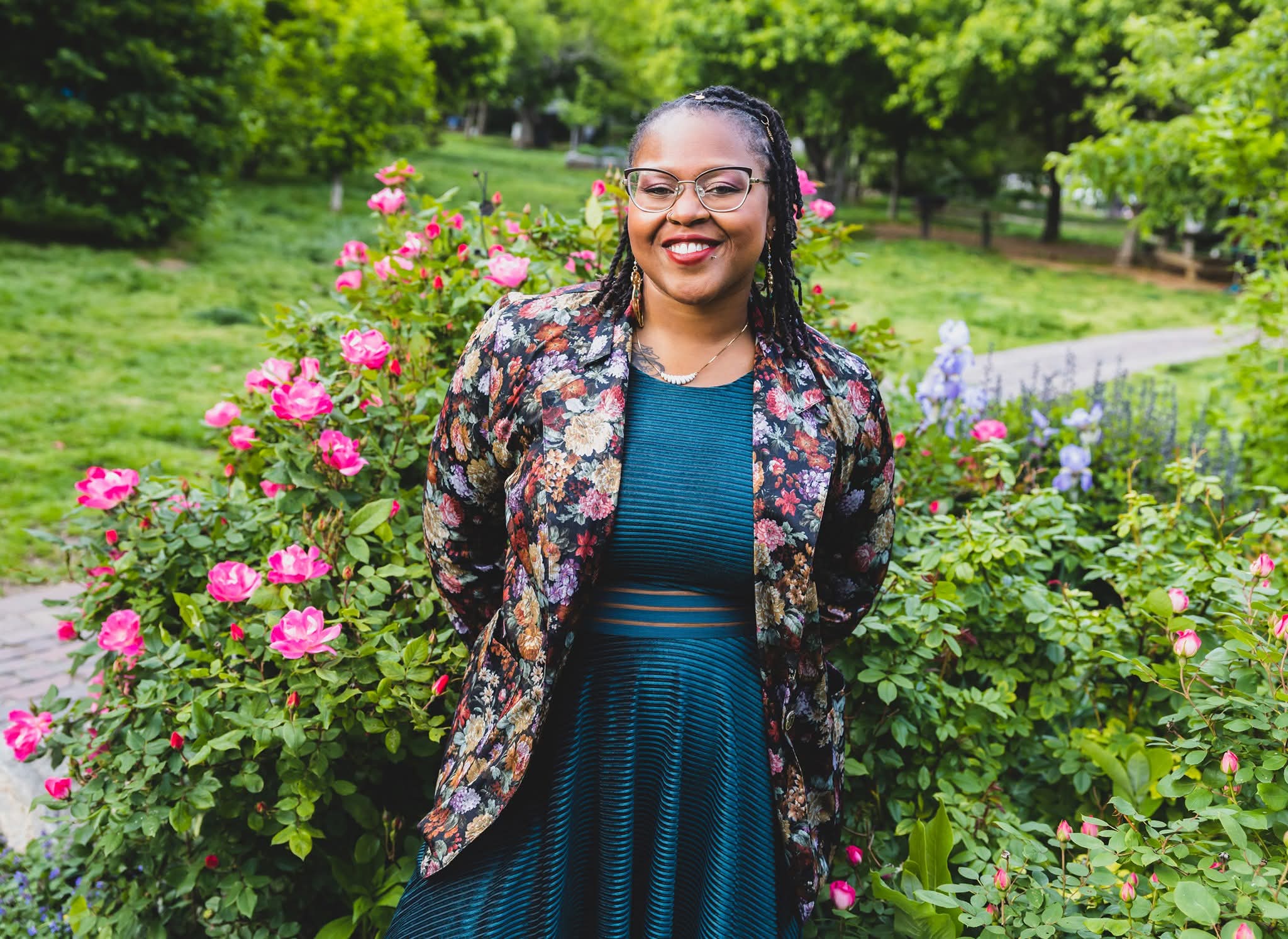 Candice, founder of The Wallflower Observer, standing among roses in a garden