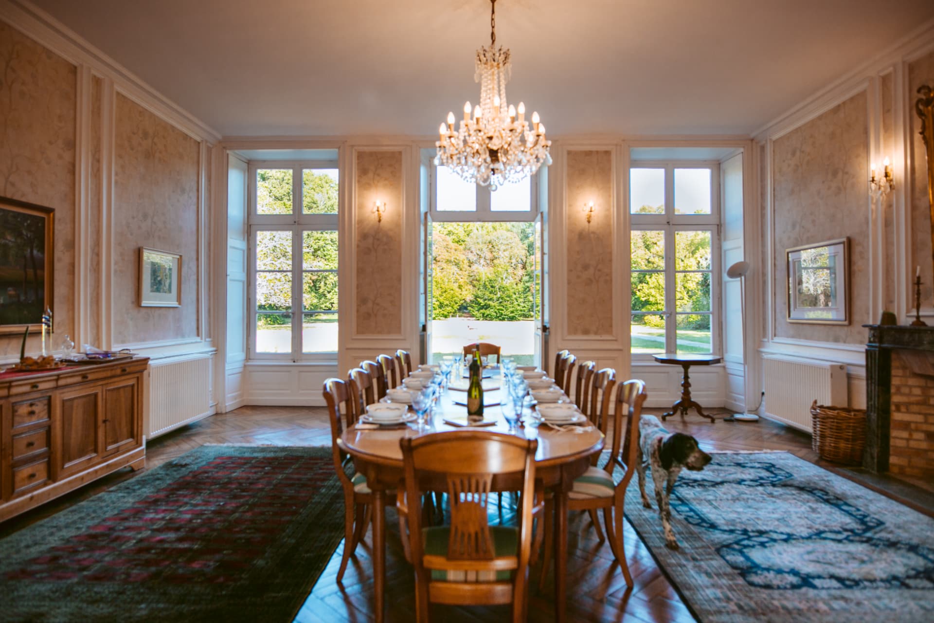 The dining hall set for dinner, the house dog passing through