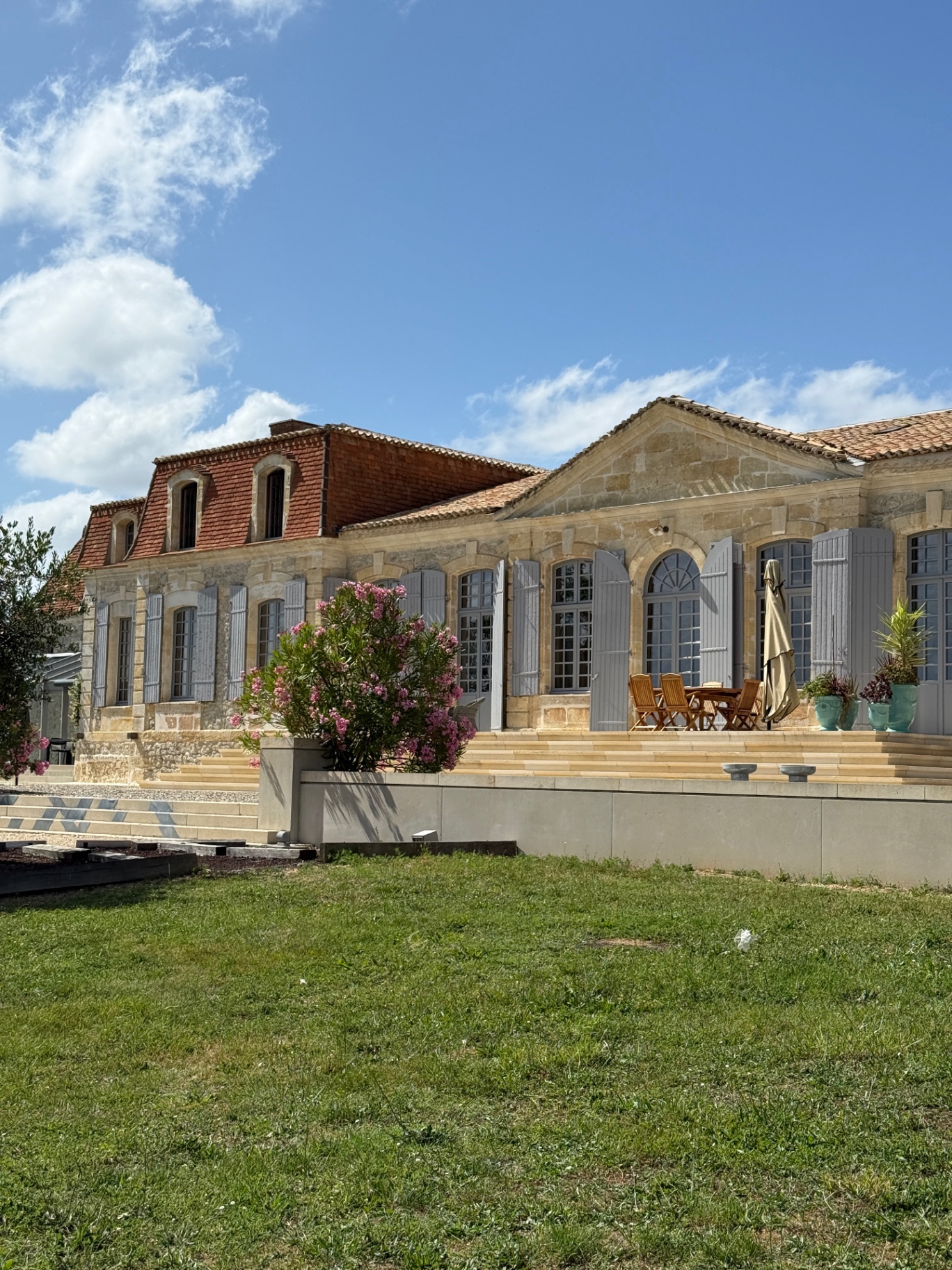 Limestone façade with grey shutters and oleanders